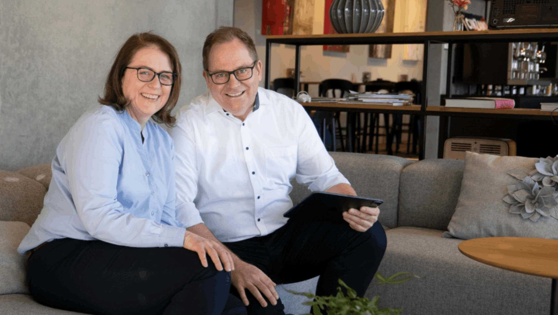 Ruth Döring und Hubertus Dejl, die geschäftsführenden Gesellschafter von GIANT-HR, gemeinsam auf dem Sofa mit Tablet.